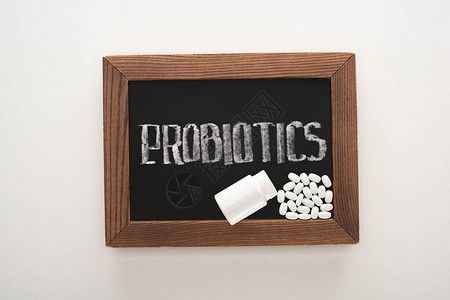 粉黑板的顶部视图前生物用药丸和容器以白背景图片