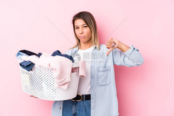 年轻的caucasian女人拿起一件脏衣服表现出不喜欢的手图片