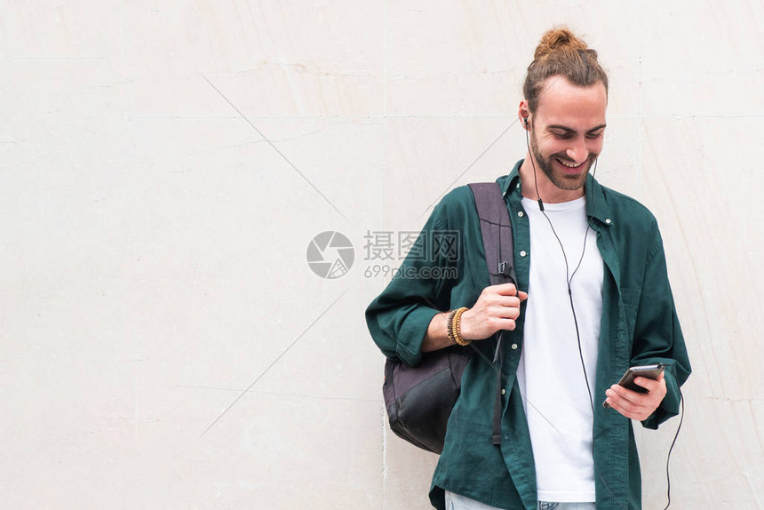 白人背景的青年男子用手机和耳听器收听音乐图片