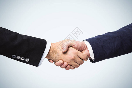两个商人手握着白墙背景交易概念背景图片