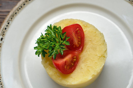 深色木质背景的白盘上放着西红柿的土豆泥餐饮菜单图片
