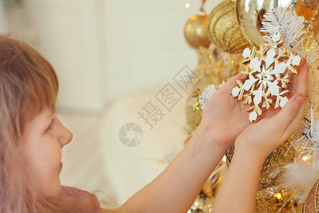 一个留着头发的金发女孩用玩具装饰圣诞树图片