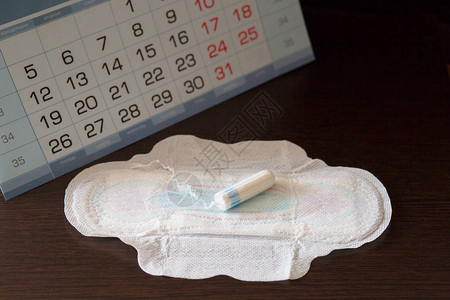 月经期间女私密卫生设备在日历上的背景位置上图片