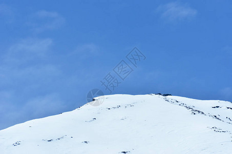 富士山的圆锥体在湛蓝的天空中升起一些薄雾从山的一侧吹过在前景中可以看到几棵树的顶部在一侧可以看背景图片