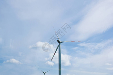 明亮的多云天空背景下的风力发电厂风力发电机特写绿色电图片