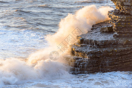 海浪拍打着分层的岩层背景图片
