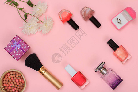 粉红色背景上的礼盒粉末指甲油香水瓶刷子和鲜花女化妆品和图片