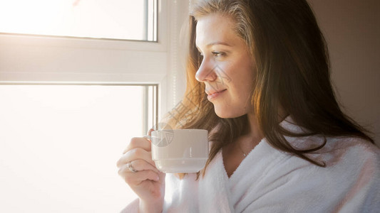微笑的女人的肖像喝着咖啡早上图片