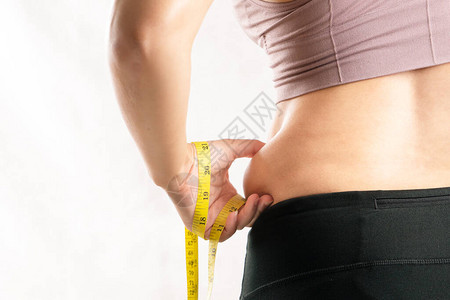 肥胖的女人手用卷尺捏在她过度的腹部脂肪腰上图片