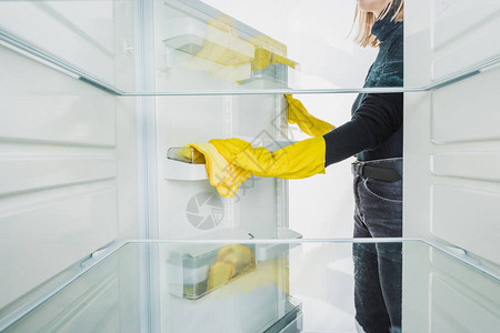 妇女清洁冰箱架子的切片视图图片