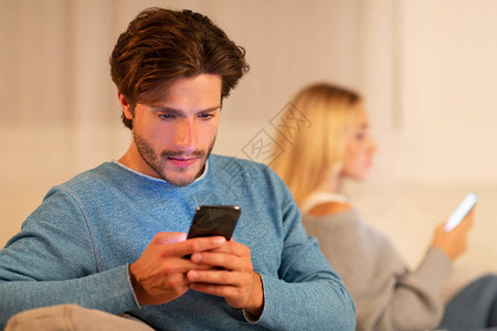 不忠在手机上欺骗丈夫聊天坐在家里的索法家妻子旁边的移动电话旁图片