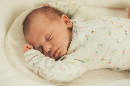 穿着白色温暖衣服在床上睡觉的新生婴儿完全放松图片