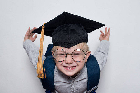 戴着学生帽子戴眼镜的可爱笑脸金发小男孩图片