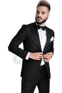 英俊的商人穿着黑色燕尾服站立和固定夹克图片