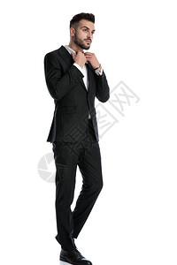 一位身穿黑色燕尾服的年轻正式商人在修他的衬衫衣领时高清图片