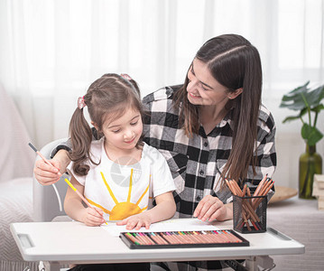 一位带着孩子的母亲坐在桌旁做作业孩子在家学习在家上学图片