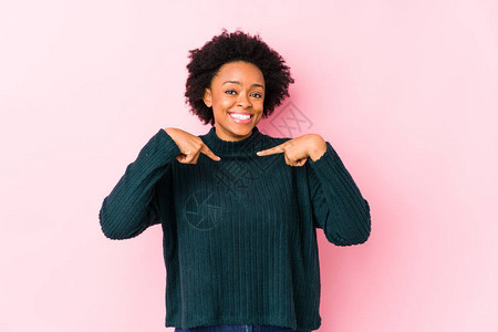 在粉红色背景下中年的非裔美国妇女以手指尖笑得非常广泛图片