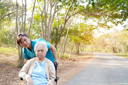 护理医院公园坐在轮椅上的亚洲老年或老年妇人患者的医生帮助和护理图片