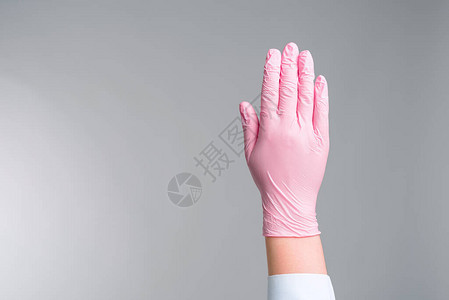 近距离医生用粉红色橡胶手套的手展示了灰色背景的止步手图片