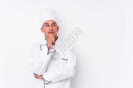 年轻的拉丁厨师长孤立地看着侧面充满怀疑图片