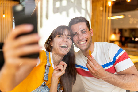 肖像幸福的情侣在咖啡馆用手机自拍图片