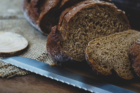 用刀切面包在木桌上切黑麦面包质朴图片