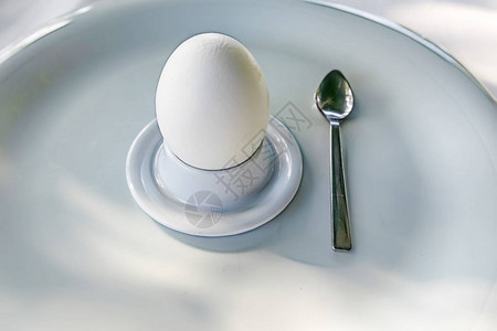 用白盘子上的小勺子把鸡蛋放在蛋杯里图片