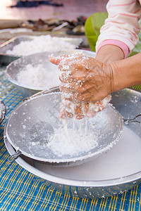 女人手用新鲜磨碎的椰子肉制作椰奶用于烹饪图片