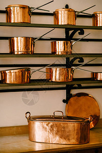 架子上放着用铜制成的长柄勺和平底锅图片