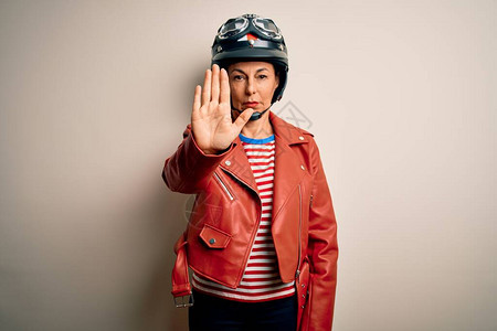 身着摩托车头盔和白色外衣的中年摩托骑车妇女用手掌停止歌唱图片