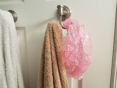 用粉红色淋浴帽挂在浴室门的钩子上的白毛背景图片