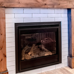 方形作物现代壁炉与木框架靠在客厅的白色口音墙上壁炉上方可以看到装饰镜图片