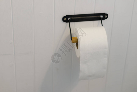 手软卫生纸卷在浴室的白色墙壁上图片