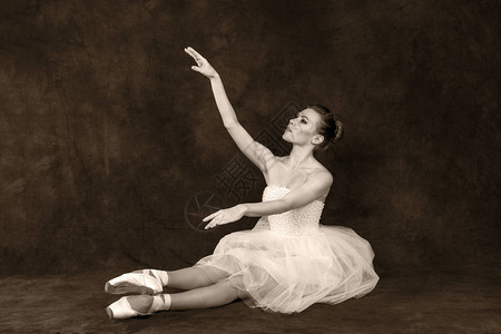 身着经典白色礼服和指尖的古老芭蕾舞女歌舞者在黑暗背景下跳舞图片