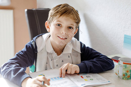 可爱的快乐学校孩子男孩在家做作业的画像小孩用彩色铅笔在室内写字小学和教育孩子学习图片