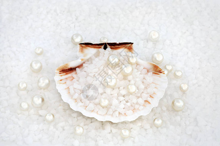 牡蛎珍珠与海盐在形成背景的扇贝壳中图片
