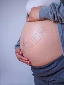 孕妇抚摸她的腹部关闭图片