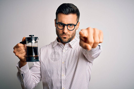 年轻英俊的男人用法式咖啡机在孤立的背景下煮咖啡图片