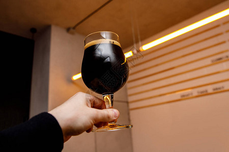 黑啤酒杯在手中酒吧内部图片