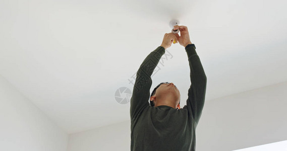 男人在家里把灯安装在天花板上图片
