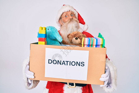 穿着圣诞老人服装的老人拿着捐赠箱微笑着看一边图片