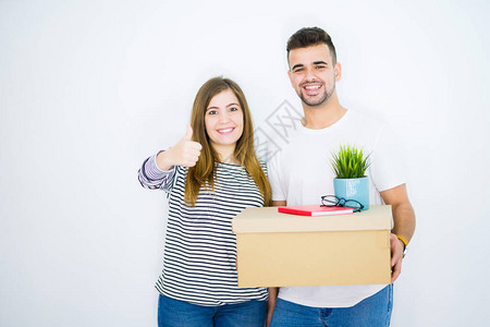 带着纸板盒的年轻夫妇在白色孤立的背景上搬进新家快乐地笑着做好牌子图片