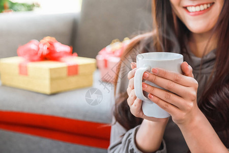 女青年用白色杯茶咖啡和美丽的礼品盒作为背景图片