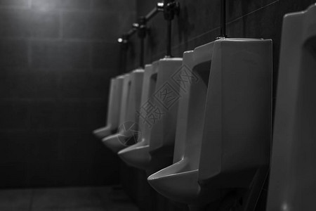 男公共厕所的白色小便池连续在男洗手间的陶瓷小便池男膀胱健康与尿失禁问题概念尿路感染男厕所WC图片