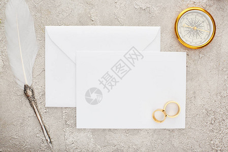 结婚戒指和毛笔在白色空白卡上金罗盘图片