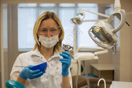 女牙医在疗办公室背景下戴着呼吸面罩和工具医学口腔医学和图片
