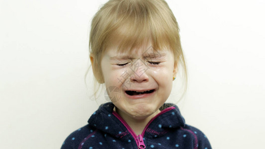 蹒跚学步的小女孩哭着流泪的画像在白色背景上隔离童年的概念儿童情绪的工作室拍摄特写金发小孩图片