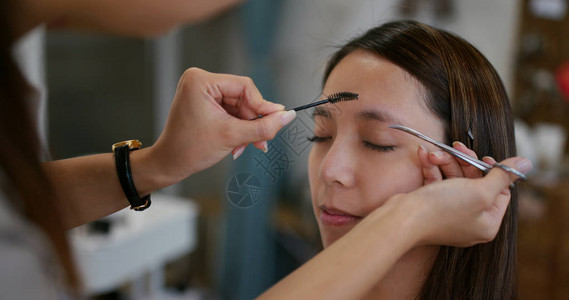 化妆师在工作室为女模特塑造眉毛图片