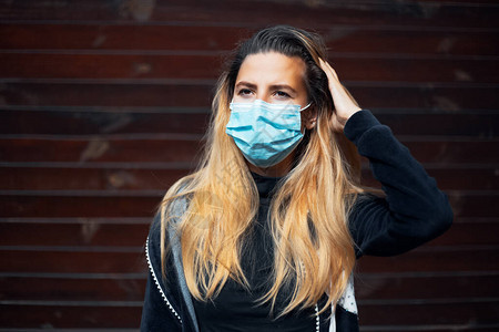 身戴医疗流感面具的年轻女孩脸部与冠状对抗的外门肖像图片