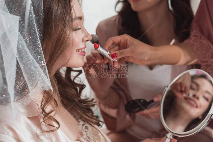 多族裔妇女用美容刷和口红的化妆品在白背景新娘上装饰的被割的多图片